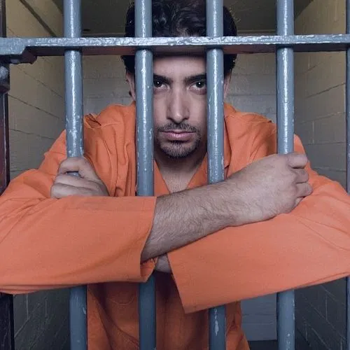 An inmate staring at the camera while behind bars.